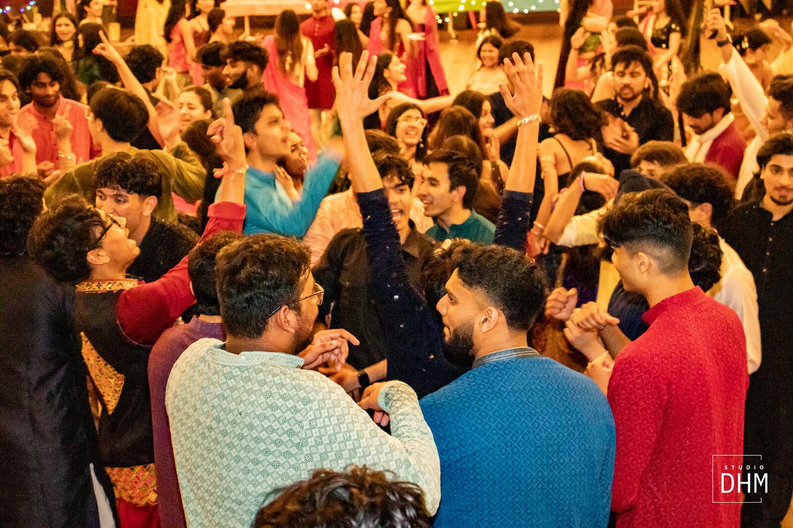Hands raised together in a golden-lit hall at a MUIC cultural night
